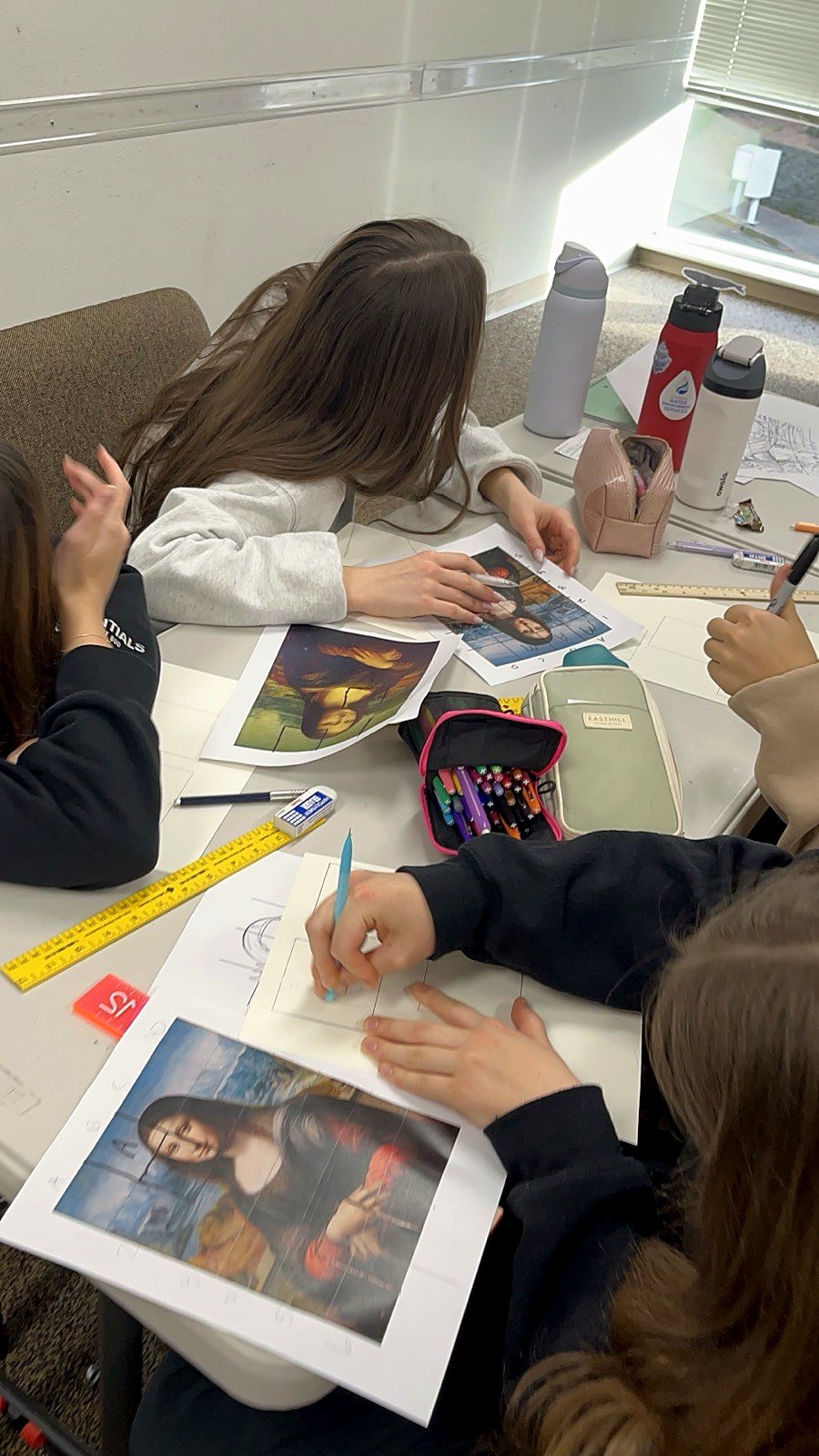 Students drawing portraits in art class using the grid method